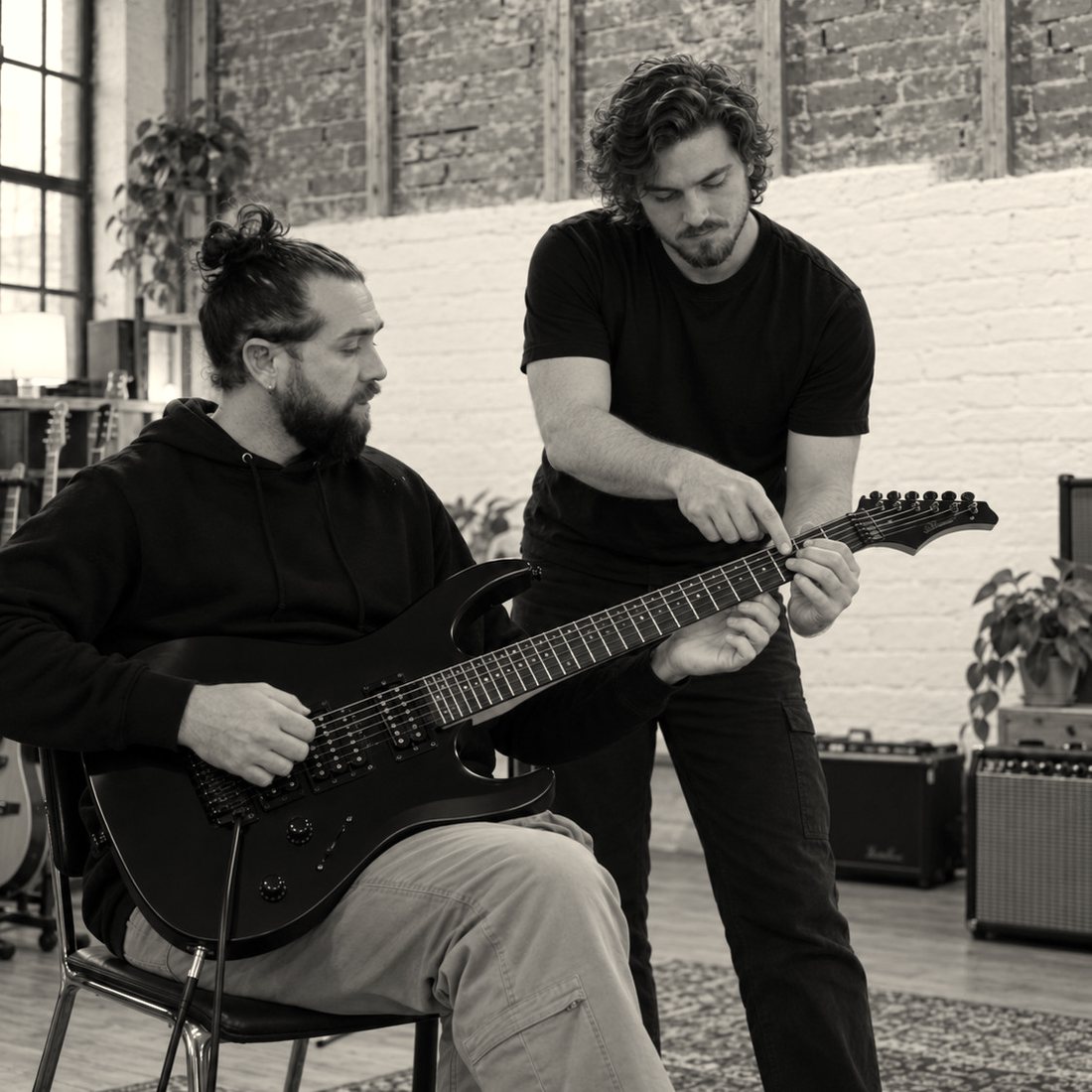 Adam Cole showing an adult student a chord on an electric guitar